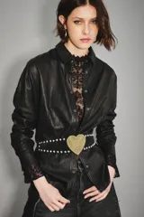 Camisa de cuero ovino color verde oliva, con cuello clásico, cierre frontal con botones y mangas largas con puños abotonados. Presenta un corte holgado y diseño tipo sobrecamisa.