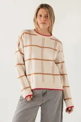 Sweater de punto con diseño de cuadros en tonos beige y marrón, cuello redondo y detalles de borde en color rojo en el cuello y el ruedo.