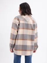 Sobrecamisa de franela con estampado de cuadros grandes en tonos blanco y negro. Presenta cuello camisero, cierre frontal con botones, mangas largas con puños abotonados y bolsillos frontales con solapa.