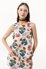 Top sin mangas con cuello a la base, estampado con flores naranjas y pájaros rojos.
