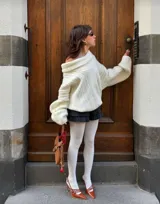 Buzo tejido de punto color crudo con diseño off-shoulder, textura acanalada y calce relajado.