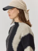 Gorro tipo pañuelo con visera rígida negra, confeccionado en lino color beige con finas rayas verticales oscuras.
