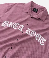 Camisa de corte oversized confeccionada en algodón, con estampado de cuadros tipo pied de poule en color rojo y blanco. Presenta cuello inglés, cierre frontal con botones y estampado lettering Breakout en el frente.