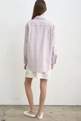 Camisa de jean azul, de corte holgado y manga larga, con cuello camisero y cierre frontal de botones oscuros.