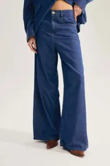 Jean de denim azul oscuro con calce de pierna ancha y fluida, tiro alto y aplique de parche en la cintura.