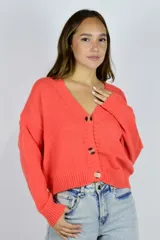 Saco tejido de punto color coral, con escote en V, mangas largas y cierre frontal de botones carey.