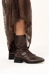 Bota de caña media con textura de reptil, confeccionada en cuero color chocolate. Presenta puntera cuadrada, taco bloque y cierre lateral interno.