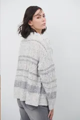 Sacon de tejido de punto grueso con diseño de ochos y rayas horizontales en contraste. Presenta cuello en V, cierre frontal con botones oscuros y mangas largas con puños acanalados.