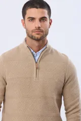 Buzo tejido texturado color beige, con cuello alto y cierre frontal parcial con detalle de cuero.