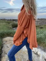 Polerón blanco de morley con cuello alto y volados en ruedo y puños.