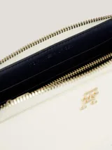 Billetera Tommy Hilfiger Iconic de poliuretano color blanco, con cierre de cremallera, insignia metálica del monograma TH y múltiples ranuras interiores para tarjetas, monedas y billetes.