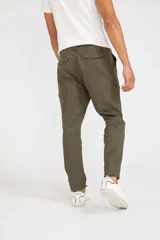 Pantalón cargo color beige de corte slim, con cierre y botón frontal, y bolsillos laterales tipo cargo con cierre.