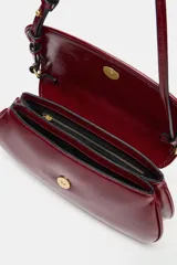 Bolso de hombro tipo baguette con acabado brillante, solapa frontal con cierre de botón imantado y asa ajustable.