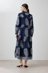 Maxi vestido azul marino con estampado de arabescos en blanco, corte camisero, cuello clásico, mangas 3/4 y falda escalonada.