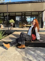 Chaleco negro con interior de corderito, con detalles en color naranja y ribeteado en marrón.