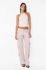 Pantalón cargo deportivo color beige, de corte recto y tiro bajo, con recortes y múltiples bolsillos laterales y traseros con tapa y botón a presión. Cierre frontal con cremallera y botón.