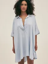 Túnica corta de lino color azul celeste, con cuello camisero, escote en V y mangas cortas.