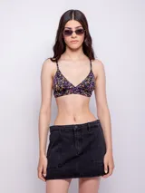 Top de bikini negro con estampado floral multicolor, corte triangular fijo, breteles finos regulables, gancho en la espalda, forro interior y copas desmontables.