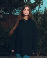 Sweater negro de punto con cuello redondo y corte holgado. Diseño con motivo de zurcido en la manga izquierda.