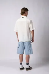 Camisa de manga corta confeccionada en una mezcla de lino y viscosa, con cuello plano y cierre frontal de botones. Presenta un diseño de calce regular con textura natural y acabado ligero.