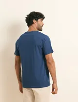 Remera básica de algodón color beige, de manga corta, con cuello redondo y un pequeño detalle bordado en el pecho.
