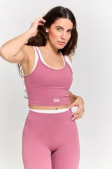 Conjunto deportivo de dos piezas en color rosa, compuesto por un top corto con tirantes finos y logo estampado, y un pantalón de corte acampanado con cintura alta.