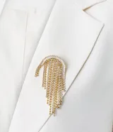 Blazer estructurado color blanco de la marca Cortelle, con solapa clásica, bolsillos frontales con solapa, mangas largas y cierre frontal de botones. Incluye un broche decorativo dorado con flecos de pedrería.