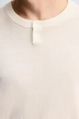 Jersey de punto con mezcla de algodón y cashmere, de corte regular y manga larga. Presenta cuello redondo con cierre frontal de dos botones y acabados en rib.