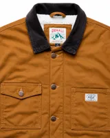 Campera de estilo workwear color camel, confeccionada en canvas resistente con interior de corderito sherpa. Presenta cuello de pana en color marrón oscuro, cierre frontal con botones metálicos color cobre, cuatro bolsillos frontales y un bolsillo interior.