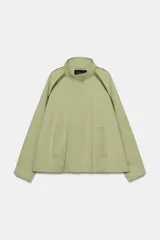 Cazadora ZARA Woman Collection color verde militar, con cuello alto, manga larga y bolsillos frontales. Cuenta con detalles de vivos a contraste en los hombros, bajo elástico asimétrico y cierre frontal oculto con cremallera y botones.