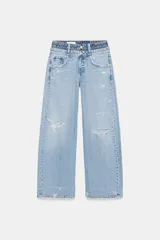 Jeans de tiro medio, color azul claro, con doble cinturilla y trabillas. Presenta cinco bolsillos, detalles de rotos y cierre frontal con cremallera y botones.