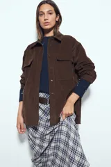 Sobrecamisa de pana color marrón oscuro, con diseño de corte amplio, cuello camisero, cierre frontal con botones y bolsillos con solapa en el pecho.