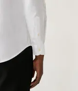 Camisa blanca de algodón, corte slim fit, manga larga y cuello clásico.