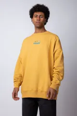 Buzo de cuello redondo y corte oversize, confeccionado en tela rústica color amarillo. Presenta un pequeño estampado central en el pecho con un avión y olas.