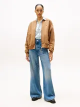 Buzo bomber color marrón confeccionado en felpa de algodón regenerativo, con cierre de cremallera, cuello, puños y ruedo acanalados. Presenta el logo de Tommy Hilfiger bordado en el pecho y en el puño.