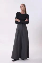 Pantalón de vestir de corte sastrero y pierna ancha (wide leg), confeccionado en tejido de lana gris. Presenta cintura alta con doble botón y pinzas frontales que aportan volumen y caída fluida.