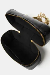 Bolso tipo vanity de estructura rígida y diseño acolchado con pespuntes. Cuenta con asa de mano superior y una cadena decorativa dorada con charms colgantes. Incluye cierre de doble cremallera y correa bandolera ajustable y extraíble.