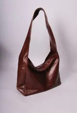 Bolso tipo hobo de cuero negro con correa ancha para el hombro.