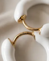 Aros tipo argolla pequeña de acero dorado con recubrimiento esmaltado en color blanco.