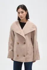 Tapado corto de paño en color beige, con cuello solapa amplio y cierre frontal cruzado con doble botonadura. Presenta mangas largas y bolsillos laterales integrados.