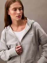 Buzo gris con capucha, cierre frontal con cremallera, logo de Calvin Klein bordado en el pecho y corte cropped.