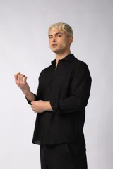 Camisa de manga larga con cuello clásico y cierre frontal de botones. Presenta un calce relajado y una textura liviana.