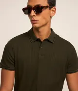 Remera polo blanca de viscosa texturizada con rayas, cuello y puños de mangas cortas en ribana con detalles contrastantes en negro.