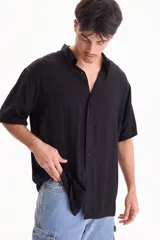 Camisa de viscosa negra de manga corta, con cuello camisero y cierre frontal de botones, de corte oversize.