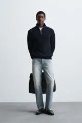 Jersey de punto perlado con cuello perkins y cierre frontal de cremallera. Presenta un corte regular fit, manga larga y acabados en rib en puños y bajo.