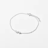 Pulsera plateada de cadena fina con tres pequeños dijes con forma geométrica y cierre de mosquetón.