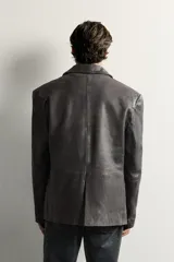 Blazer de cuero marrón oscuro, de corte regular fit, con solapas de muesca, cierre frontal de tres botones y bolsillos con solapa en la cadera.