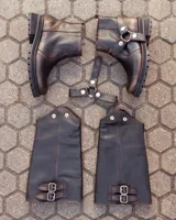 Bota de caña alta confeccionada en cuero color marrón caoba con acabado desgastado. Presenta una suela track robusta, correas con hebillas en la parte superior de la caña y un arnés decorativo con herrajes metálicos en el tobillo.