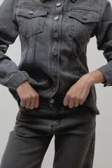 Chaqueta de denim de algodón con corte entallado en la cintura, cuello clásico, cierre frontal con botones metálicos y dos bolsillos con solapa en el pecho.