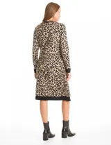 Vestido midi de tejido de punto con diseño integrado que simula un conjunto de vestido negro liso con un cárdigan largo estampado de eslabones geométricos en blanco y negro. Presenta escote redondo y mangas largas.